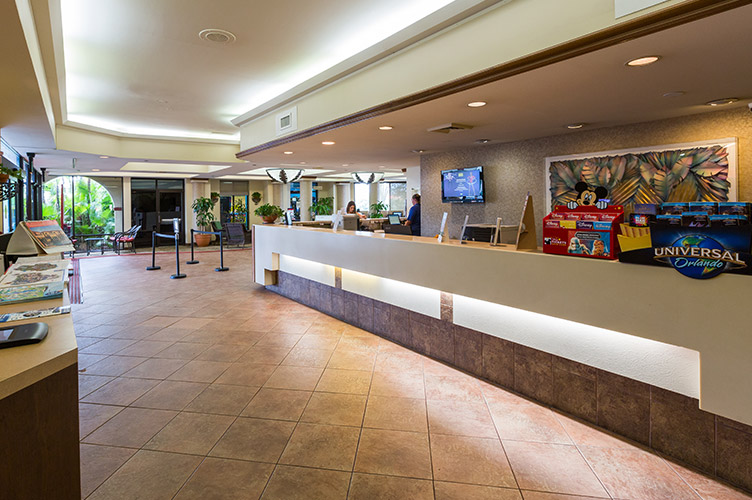 Interior shot of the front lobby at our family friendly hotel in Kissimmee, FL. Grey tile, beige colored counter tops, and plants line the entrance